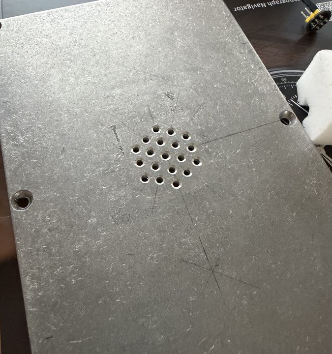 Close-up of the lid with 19 small holes drilled in a hexagon, with scribed centre lines