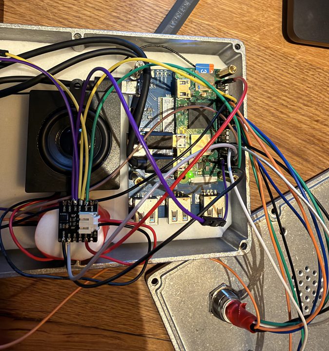 Inside the box fully wired: coloured wires from the Pi to the amplifier and buttons, the speaker on the left